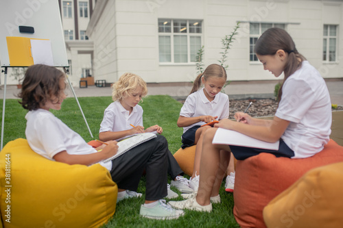 Children sitting together on bag chairs and doing homework