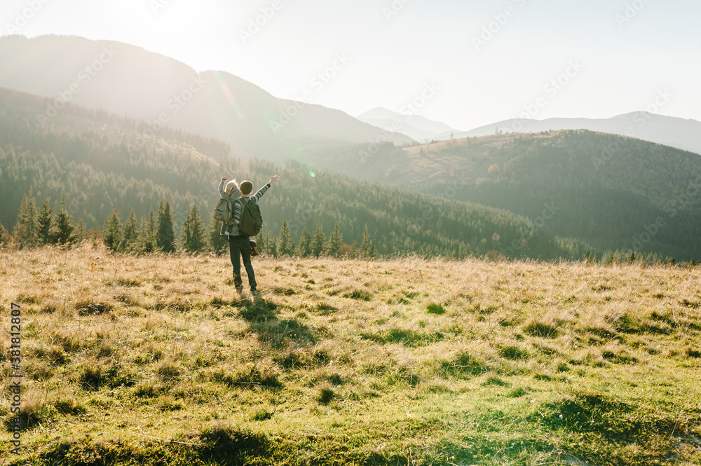 The daughter hug father on nature. Dad with backpack and child walk in the autumn grass. Family spending time together in mountain outside, on vacation. Holiday trip concept. World Tourism Day.