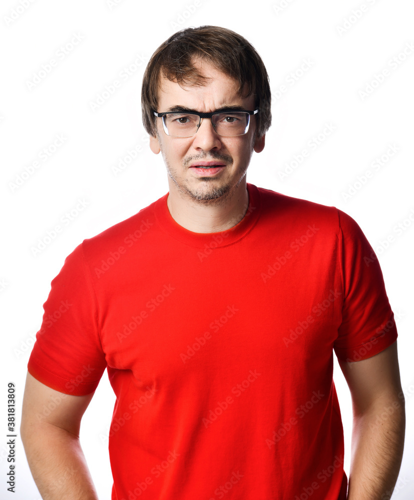 Unhappy squeamish unshaved adult man in red t-shirt and glasses looks at camera trying to see understand something Unhappy squeamish unshaved adult man in red t-shirt and glasses looks at camera trying to see understand something