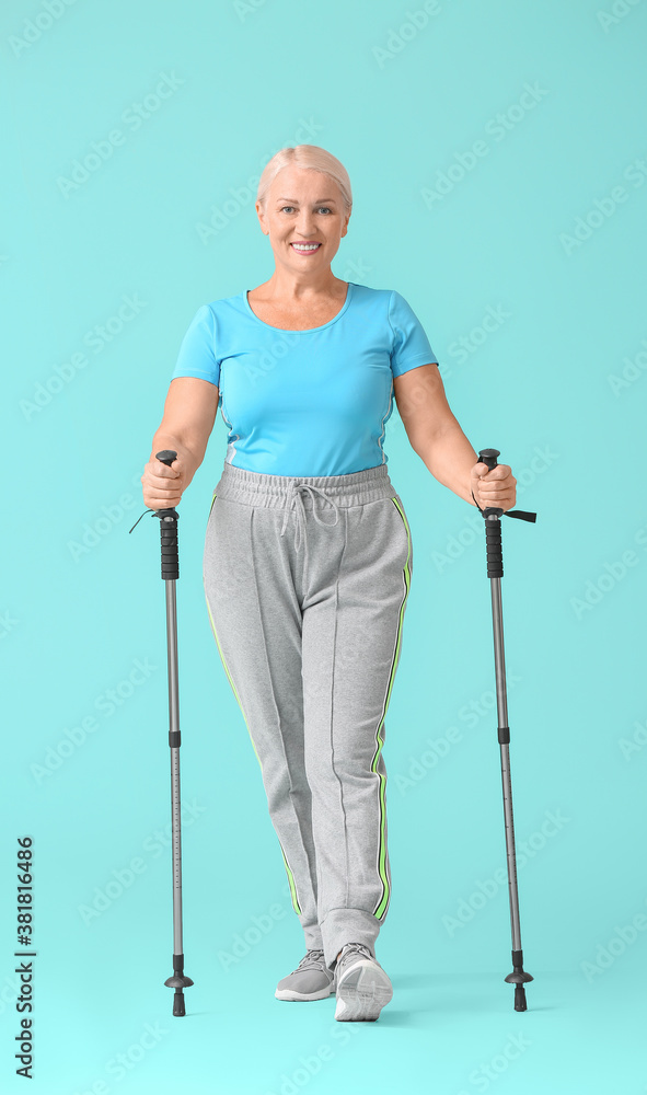 Mature woman with walking poles on color background Mature woman with walking poles on color background