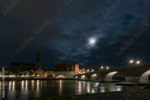 Steinerne Br  cke in Regensburg mit Dom und Donau und Mond bei Nacht mit Wolken