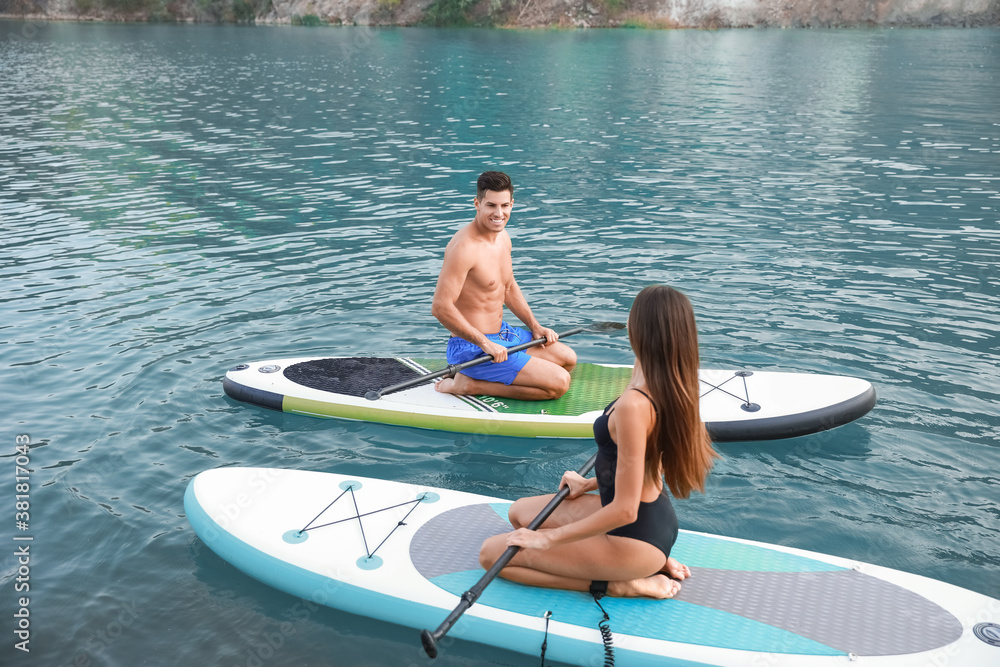 Young couple using paddle boards for sup surfing in river