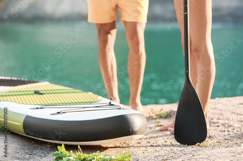 Young couple with board and paddle for sup surfing near river