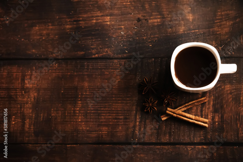 a Cup of coffee with cinnamon sticks on a dark wooden background. space for text