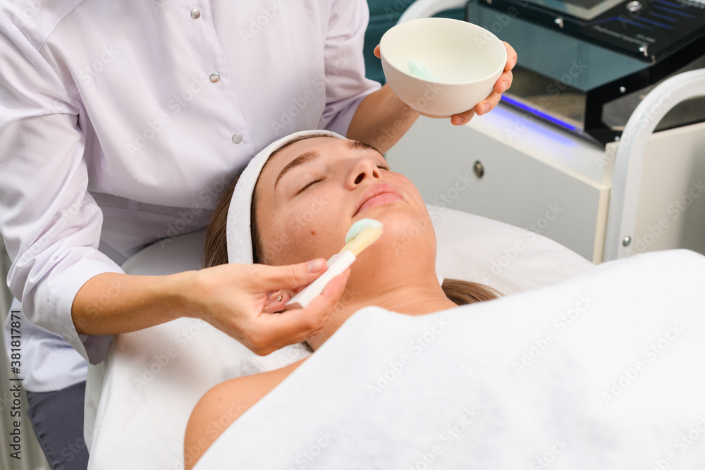 Beautician apply blue face mask on client Beautician apply blue face mask on client