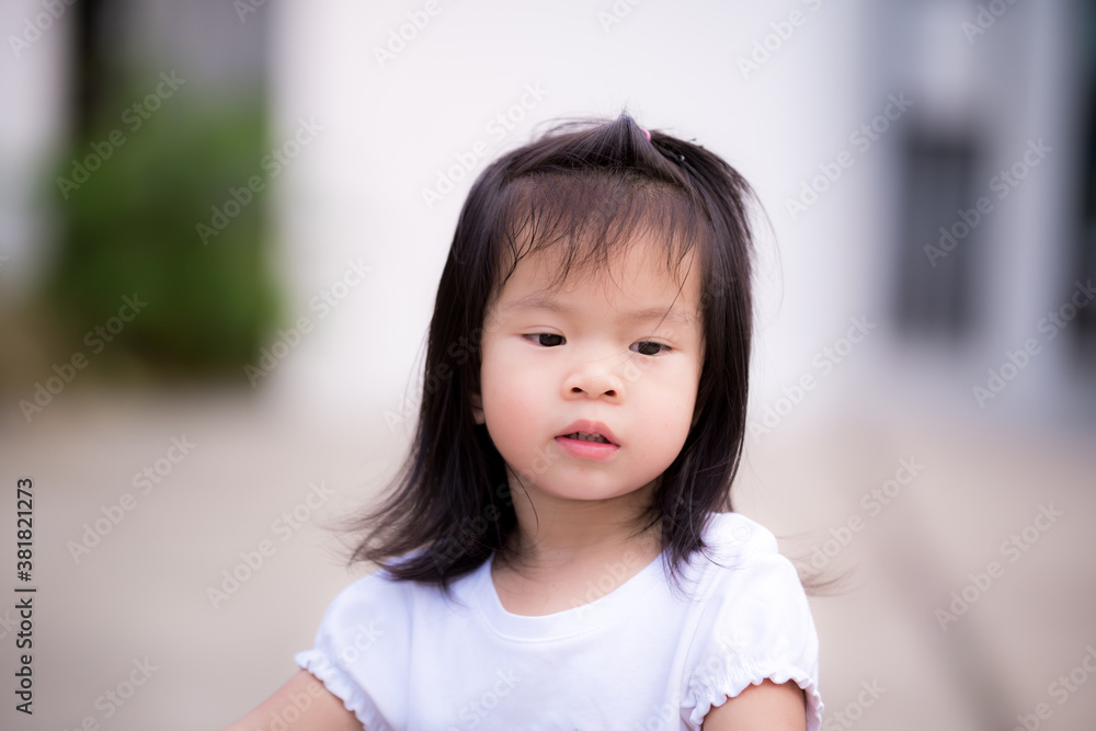 Adorable little girl standing alone and looking down at the front of her with bored face. Kid sad face is 3 years old. kid sad concept Adorable little girl standing alone and looking down at the front of her with bored face. Kid sad face is 3 years old. kid sad concept