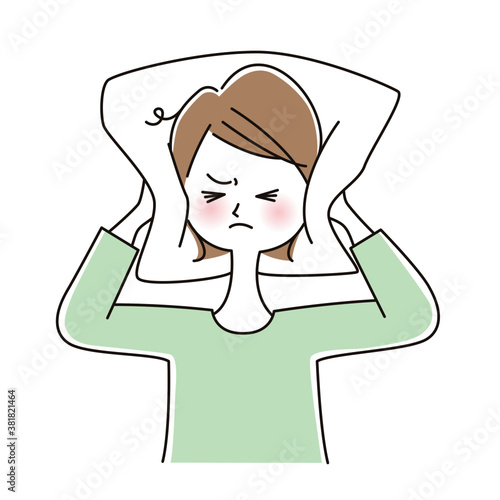 騒音でイライラして枕で耳をふさぐ女性