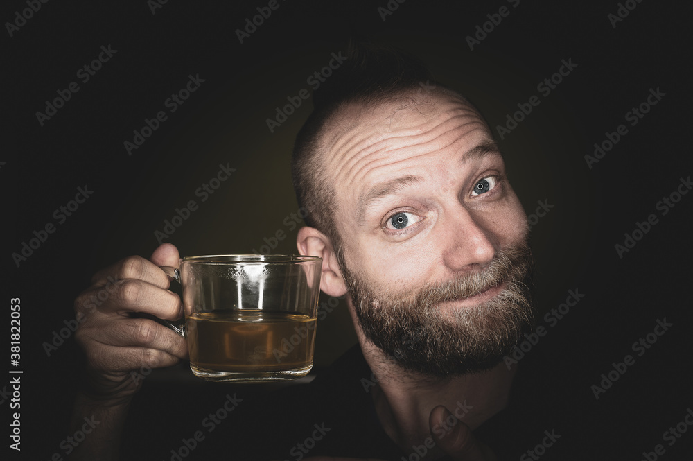 A friendly guy smiles at the camera and offers tea. A friendly guy smiles at the camera and offers tea.