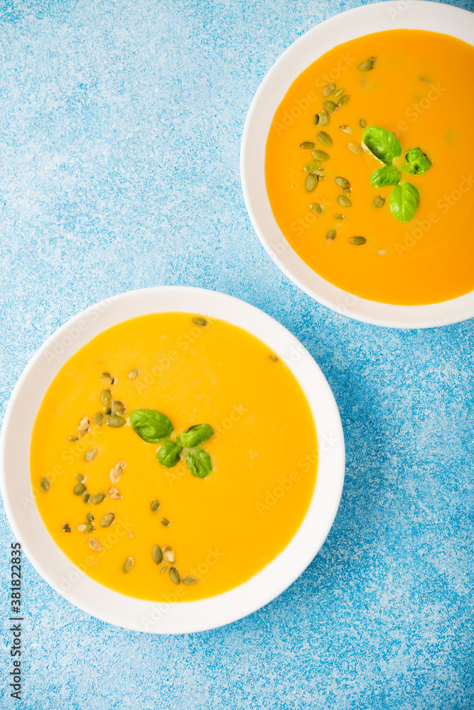 Pumpkin cream soup on a blue background, top view Pumpkin cream soup on a blue background, top view