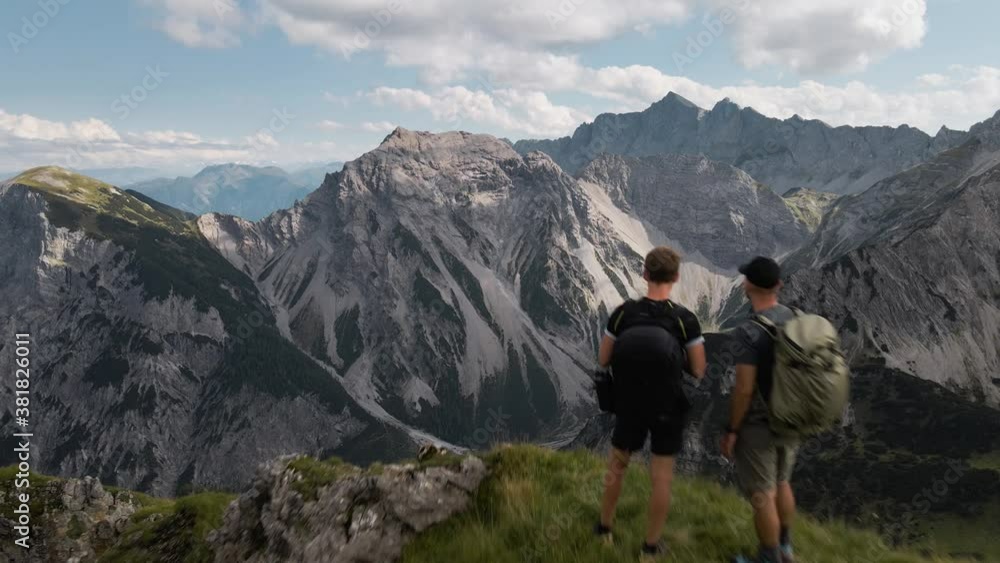 Aerial dolly out shot revealing two men standing together at the edge of a mountain Aerial dolly out shot revealing two men standing together at the edge of a mountain
