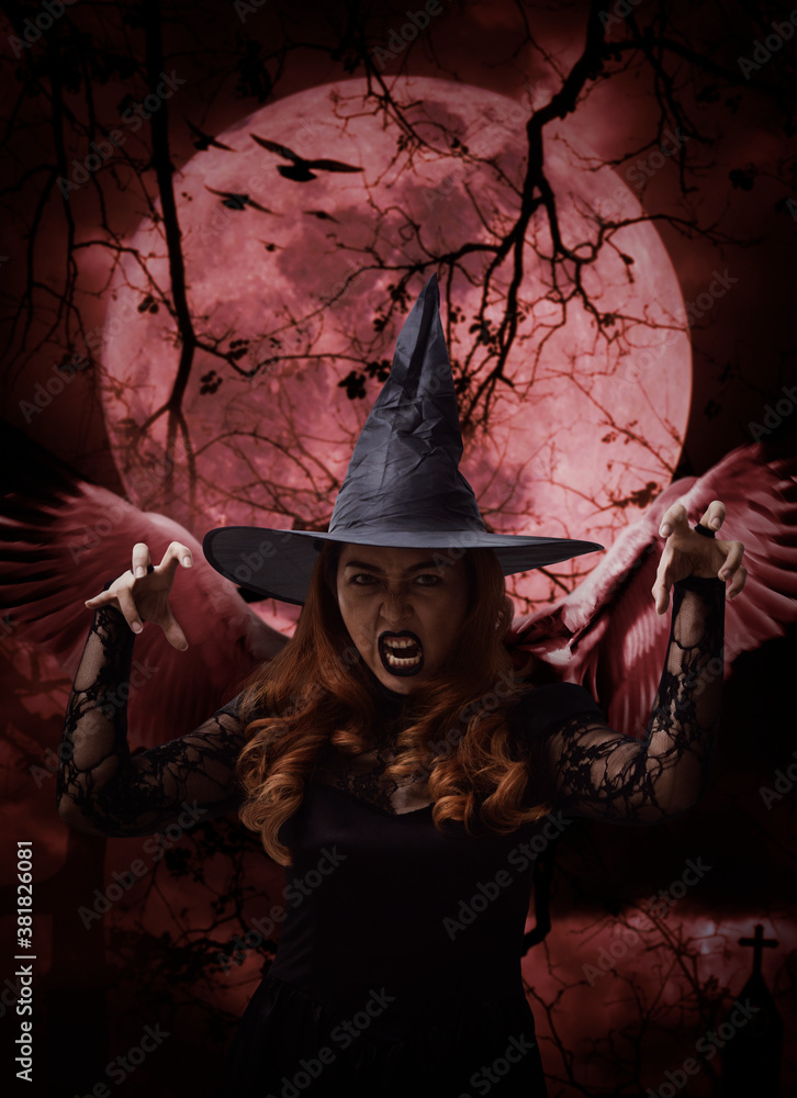 Scary halloween witch with wings standing over cross, church, crow, birds, dead tree, full moon and cloudy spooky sky, Halloween mystery concept Scary halloween witch with wings standing over cross, church, crow, birds, dead tree, full moon and cloudy spooky sky, Halloween mystery concept