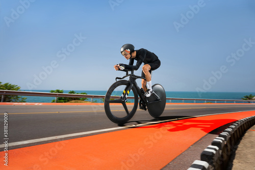 Asian cyclist practice bicycles on a triathlon on a seaside road.