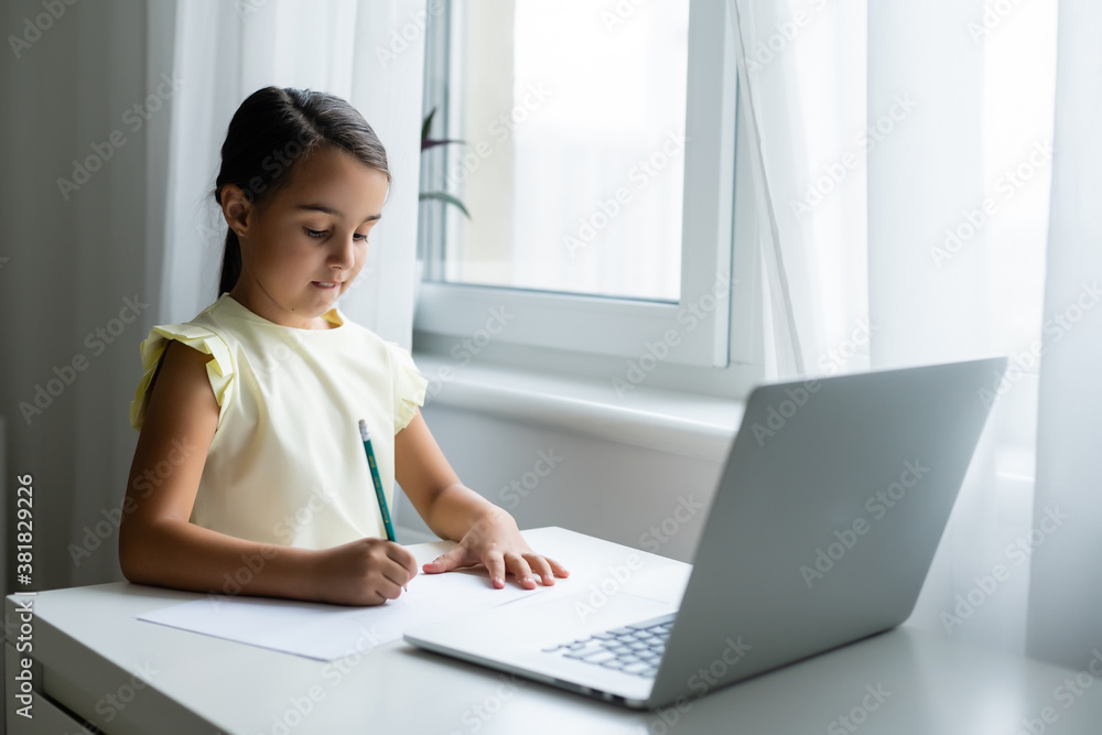 Litttle girl looking at laptop screen with expression of surprised and excitement. Smart, smilling little girl taking notes . Communication in business concept. Litttle girl looking at laptop screen with expression of surprised and excitement. Smart, smilling little girl taking notes . Communication in business concept.
