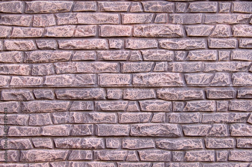 A modern stone fence in the form of an aged stone fence painted with light pink paint. A modern stone fence in the form of an aged stone fence painted with light pink paint.
