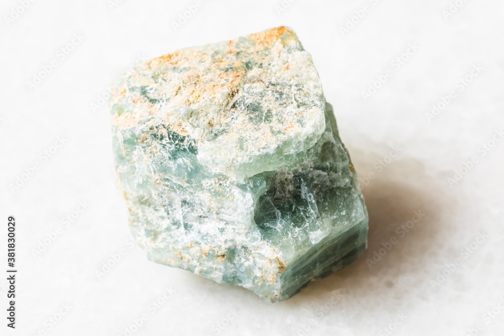 closeup of sample of natural mineral from geological collection - raw Apatite rock on white marble background closeup of sample of natural mineral from geological collection - raw Apatite rock on white marble background