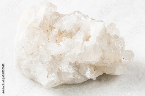 closeup of sample of natural mineral from geological collection - unpolished druse of colorless Rock crystals (rock-crystal) on white marble background from China