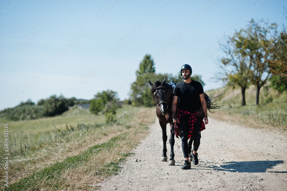 Arab tall beard man wear in black helmet with arabian horse. Arab tall beard man wear in black helmet with arabian horse.
