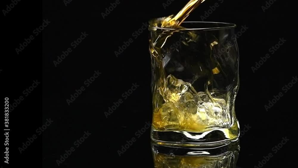 whiskey is poured into a crystal glass with ice on a black background whiskey is poured into a crystal glass with ice on a black background