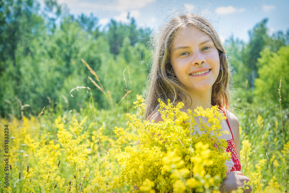 In summer, on a bright sunny day, a girl stands in a bright red dress on a blooming field. In summer, on a bright sunny day, a girl stands in a bright red dress on a blooming field.
