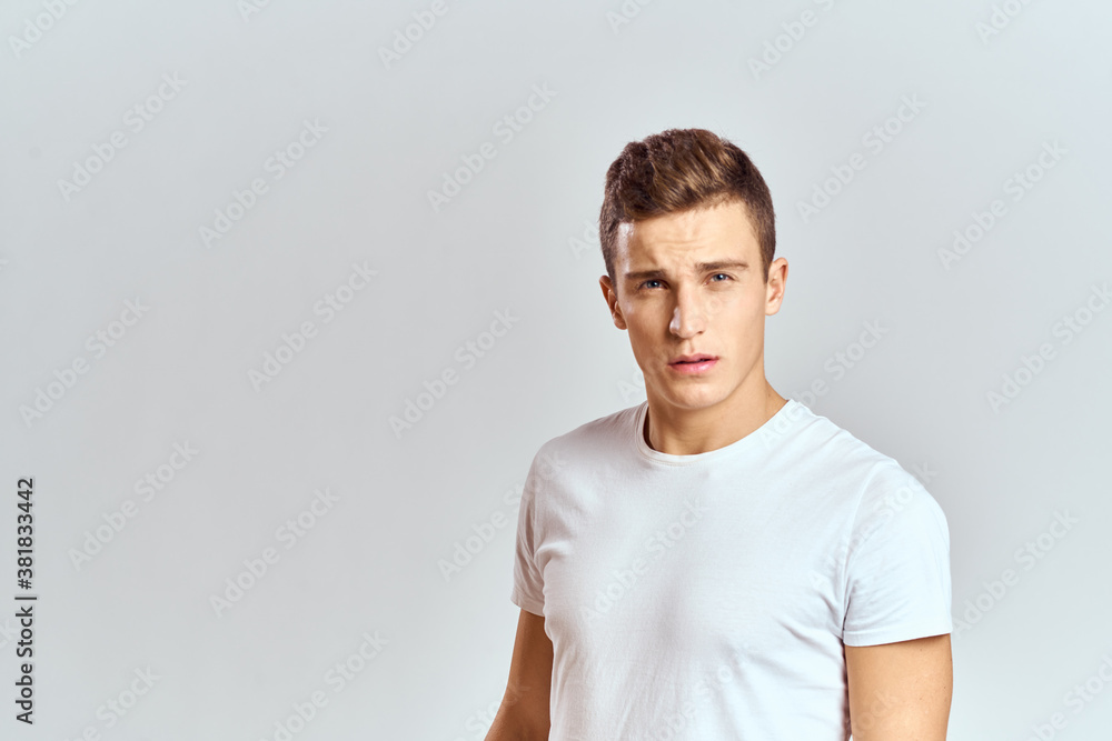 Handsome man in a white T-shirt on a light background close-up portrait cropped view Handsome man in a white T-shirt on a light background close-up portrait cropped view
