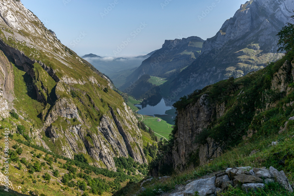 The Alpstein mountain range in Appenzell, Switzerland with the fog in the valley and the view of the Seealpsee lake The Alpstein mountain range in Appenzell, Switzerland with the fog in the valley and the view of the Seealpsee lake