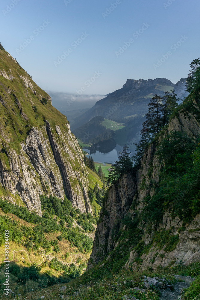 The Alpstein mountain range in Appenzell, Switzerland with the fog in the valley  and the view of the Seealpsee lake