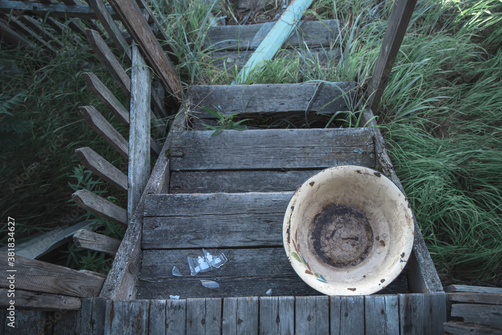 Old wooden porch of an abandoned house, dirty enameled basin. Old wooden porch of an abandoned house, dirty enameled basin.