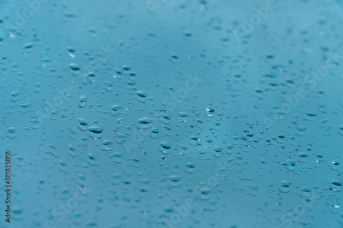 Raindrop on car window glass in morning rainy season for background or wallpaper. Drop of water on glass with blue sky and clouds.