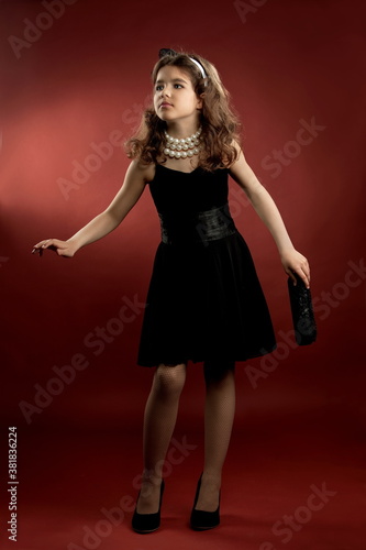 Beautiful girl in a black short dress on a red background © Alexander