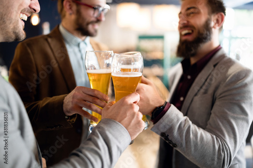 Happy young business men talking and drinking beer in a pub