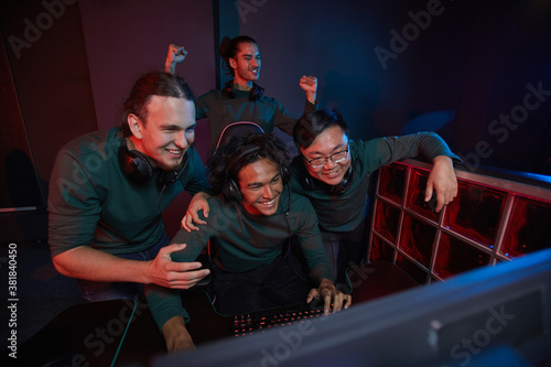 Group of excited gamers happy their victory in computer game they looking at computer monitor and smiling during their playing