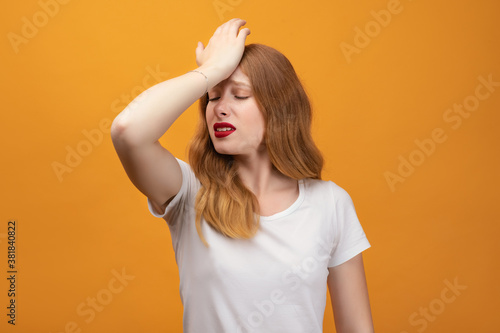 Pretty girl with wavy redhead Made A Mistake. Pensive concept. Isolated on yellow background