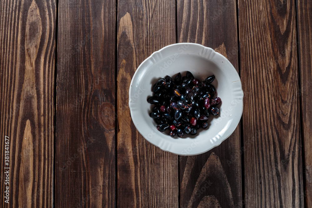 black currants in a white bowl on a wooden table. black currants in a white bowl on a wooden table.
