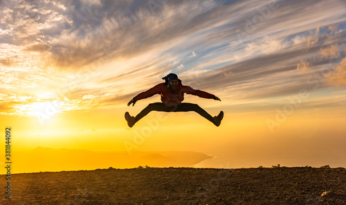 Happy man jumping for joy at sunset. Success, winner, happiness, ttavel concept. photo