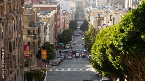 Iconic hilly street and crossroads in San Francisco, Northern California, USA. Steep downhill road and pedestrian walkway. Downtown real estate, victorian townhouses abd other residential buildings