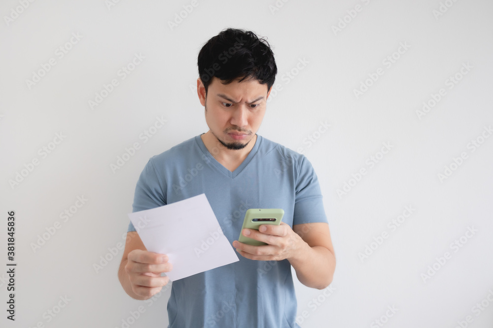 Asian man is serious by the bill and the smartphone on isolated background. Asian man is serious by the bill and the smartphone on isolated background.