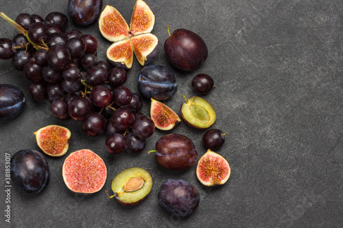 Still life of fruits. Bunch of grapes. Figs and plums. Cut figs, plum halves, plum pits.