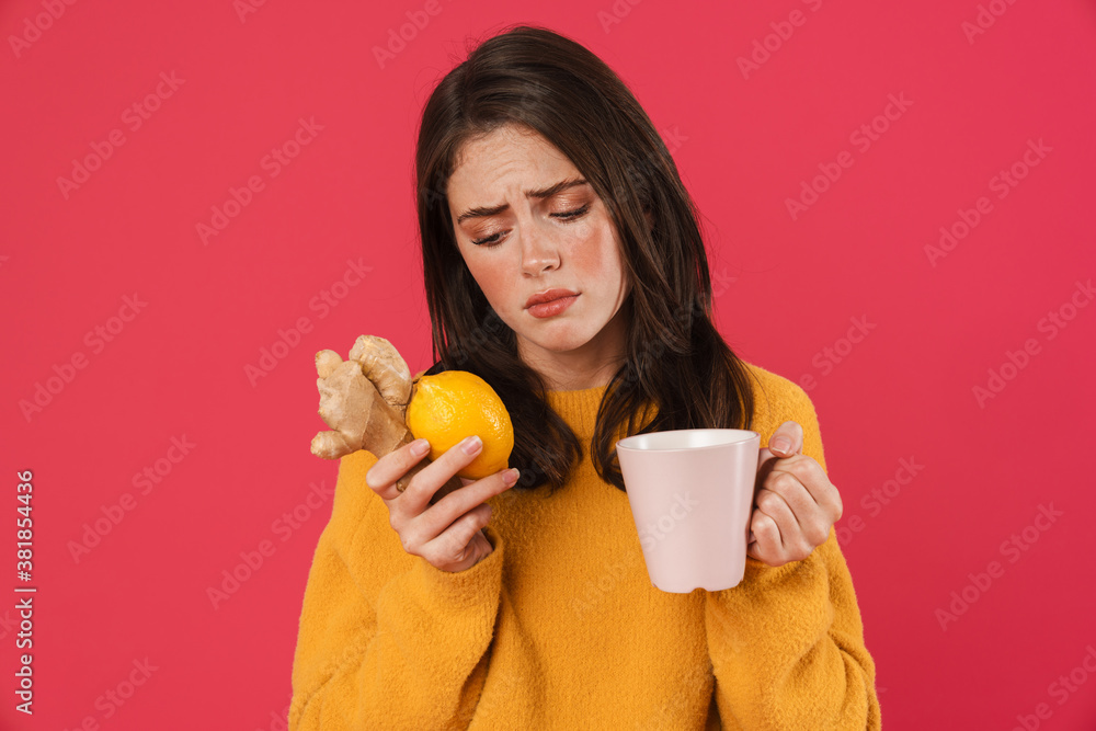 Image of unhappy girl holding lemon and ginger while drinking tea Image of unhappy girl holding lemon and ginger while drinking tea