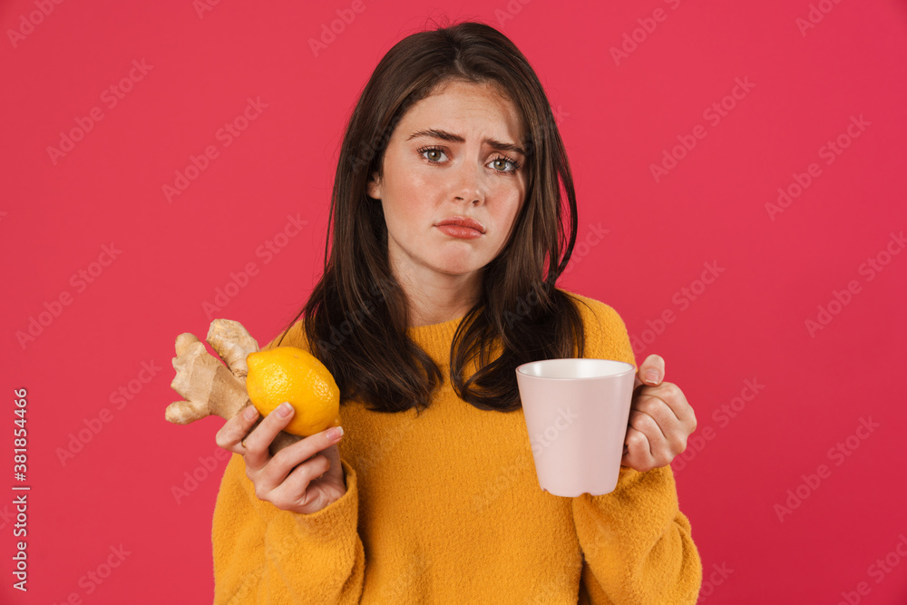 Image of unhappy girl holding lemon and ginger while drinking tea Image of unhappy girl holding lemon and ginger while drinking tea
