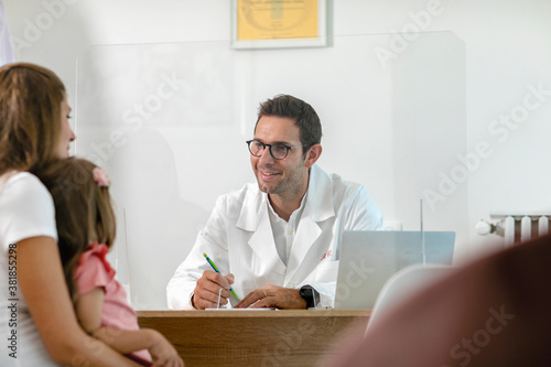 Doctor talking to patient through glass shield