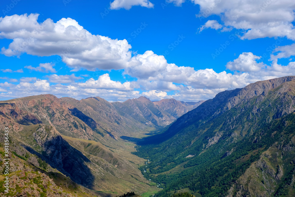 Mountain gorge landscape with cloudy blue sky. Summer nature landscape. River valley panorama. Kora river gorge in Kazakhstan, way to Burkhan bulak waterfall. Tourism in Kazakhstan concept.