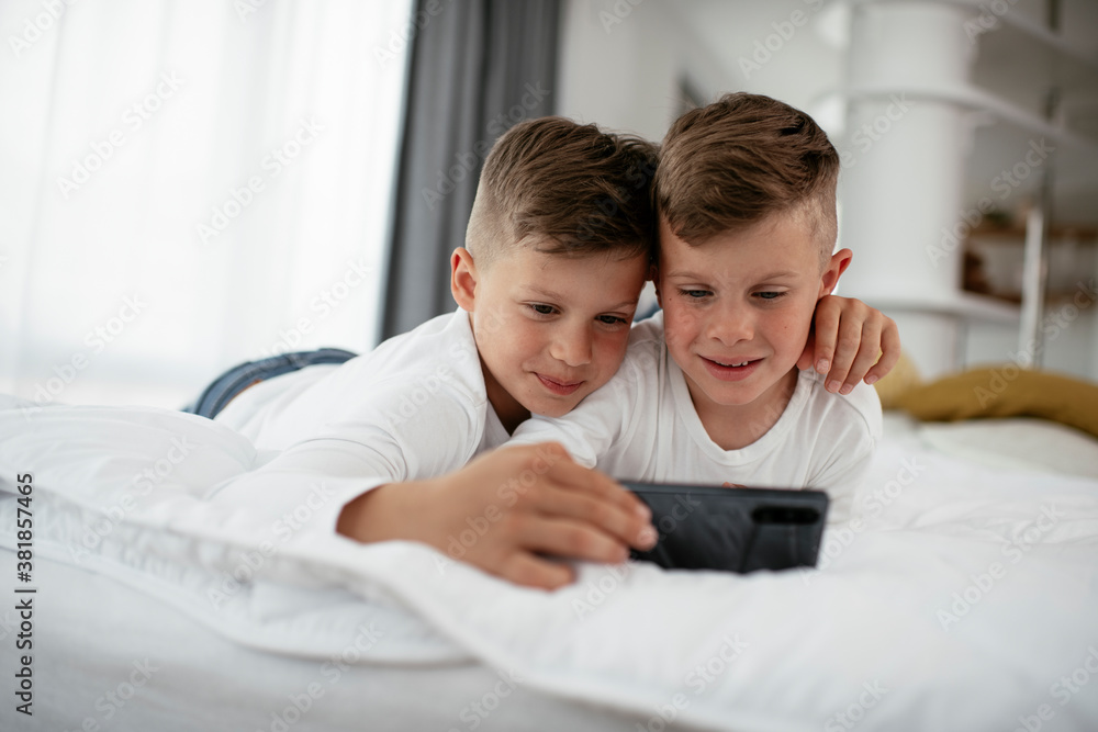 Two little brothers are playing games on the phone. Beautiful boys enjoying at home.. Two little brothers are playing games on the phone. Beautiful boys enjoying at home..