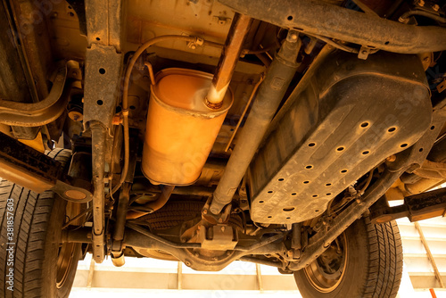 Foto Under old car closeup rear wheel axle suspension and exhaust chamber silencer muffler dirty fix repair in garage