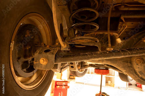 Obraz na plátně Under old car closeup rear wheel axle suspension and exhaust chamber silencer muffler dirty fix repair in garage