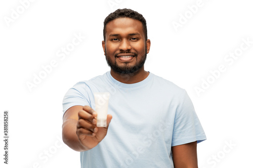 grooming, skin care and people concept - happy smiling african american showing moisturizer over white background