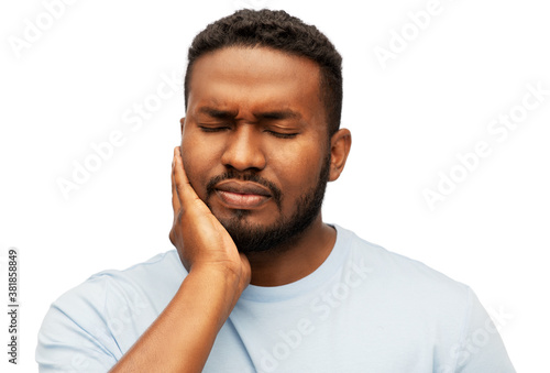 people, dentistry and health problem concept - african american man suffering from toothache over white background