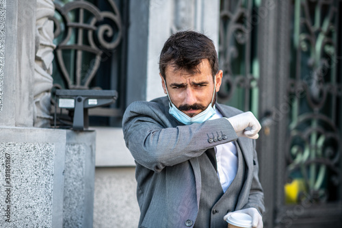 A young businessman goes to work in the morning, just sneezing into his elbow, life during a pandemic