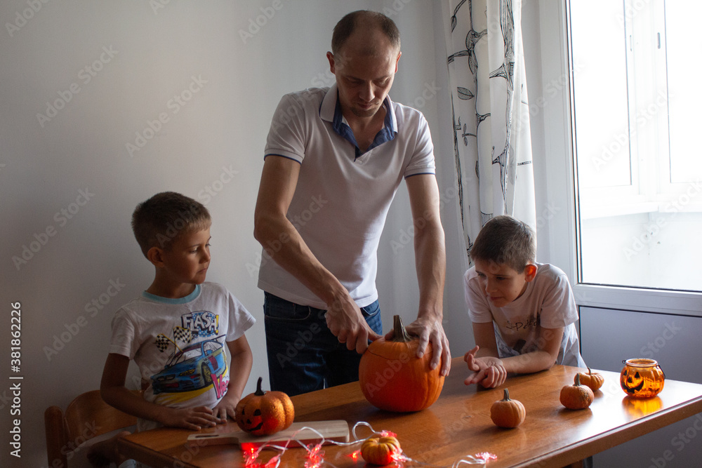 Dad and his sons make a pumpkin for halloween