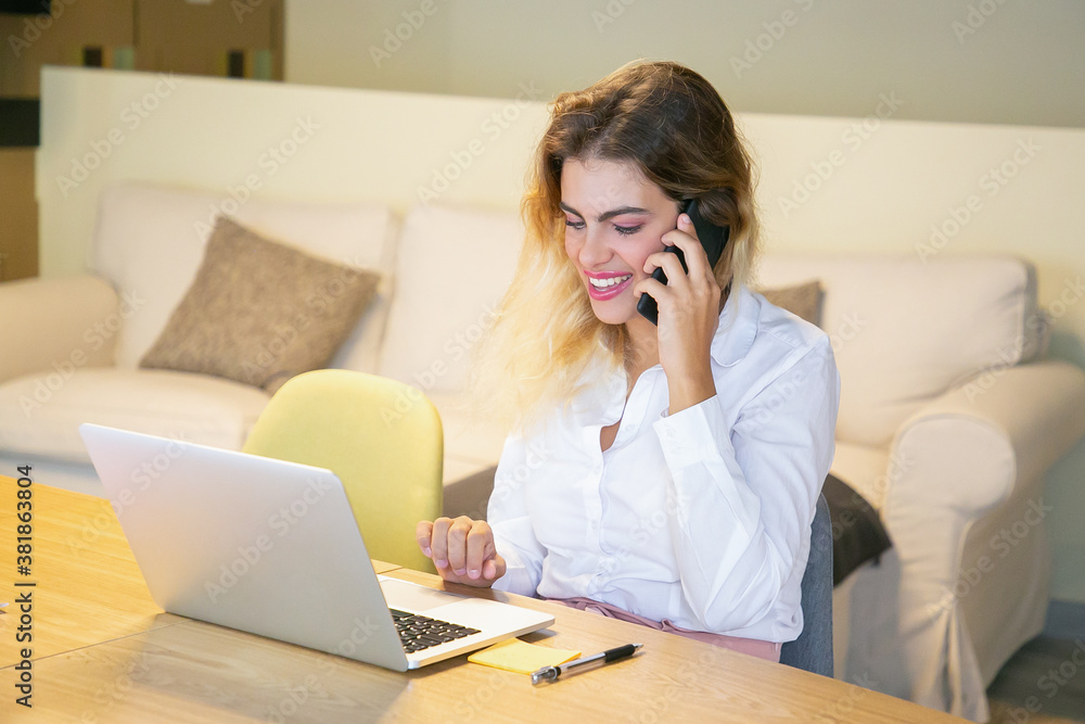 Happy successful manager discussing project with customer on phone. Business woman talking on cell in coworking office, sitting at table with laptop, smiling. Communication or multitasking concept Happy successful manager discussing project with customer on phone. Business woman talking on cell in coworking office, sitting at table with laptop, smiling. Communication or multitasking concept