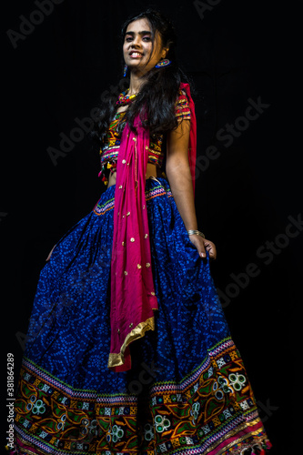 Indian girl in traditional chaniya choli for navratri with a fashionable hairstyle poses in studio on black background. Navratri is an Indian Festival and Chaniya choli its traditional costume photo